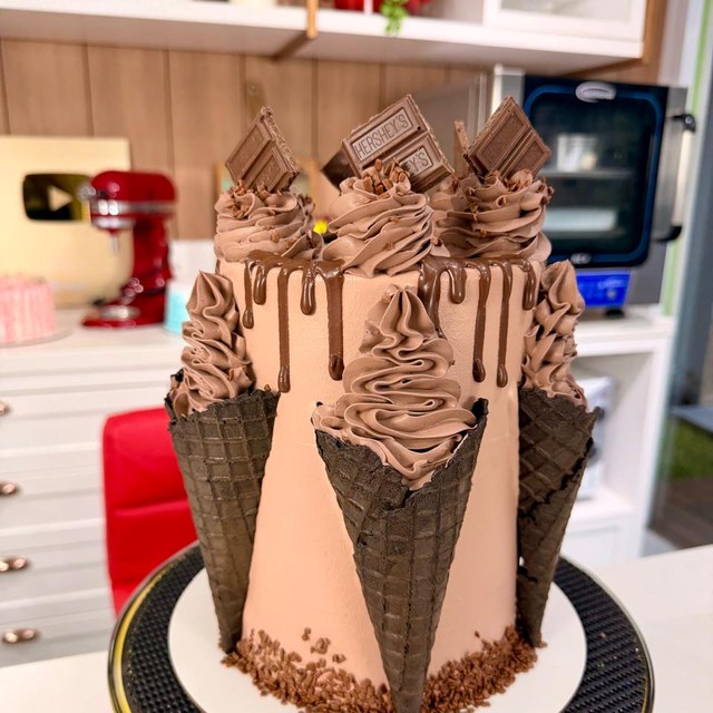 Bolo de chocolate decorado com cones e cobertura em uma mesa