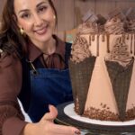 Confeiteira segurando bolo de chocolate com cones e cobertura drip