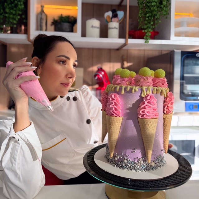 Confeiteira segurando bolo de chantilly rosa com cones